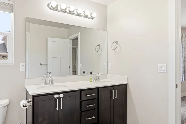 Dual vanity featuring a white countertop, undermount sinks, and wood-finish cabinetry with silver hardware