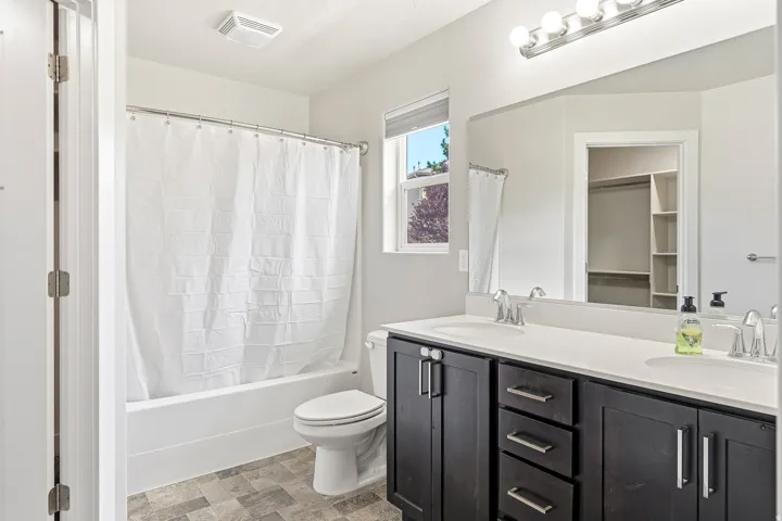 Double vanity with integrated sinks, contemporary cabinetry, a full-width mirror, and a tub/shower combination