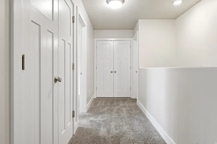 Hallway featuring recessed lighting, a built-in half-wall, and multiple paneled doors with contrasting hardware