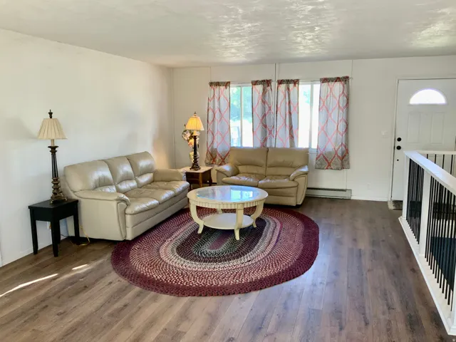 Wood-finish flooring throughout, white walls, and a white entry door with an arched window