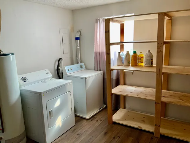 Laundry area featuring wood-finish flooring, built-in shelving, and a water heater