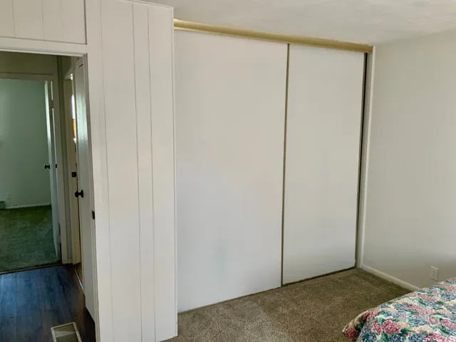 Carpeted flooring, white walls, and a white sliding door closet