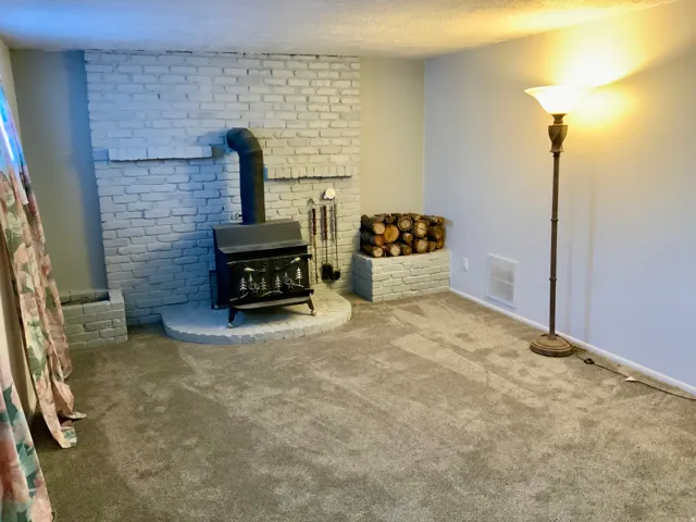 White-painted brick fireplace with a wood-burning stove and an elevated stone hearth