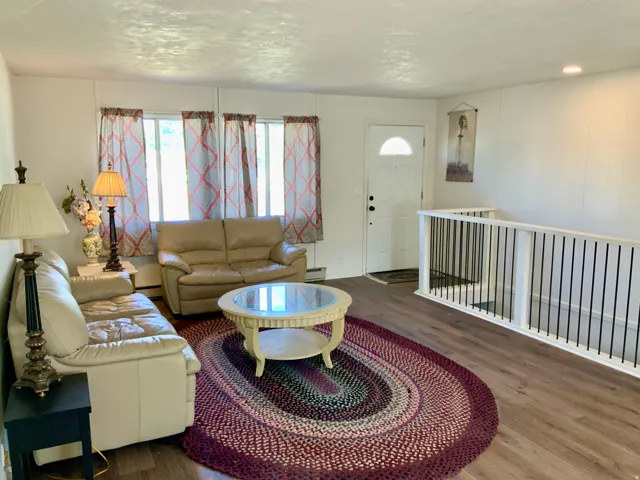 Wood-finish flooring throughout, white paneled walls, and a white front entry door with a half-moon window