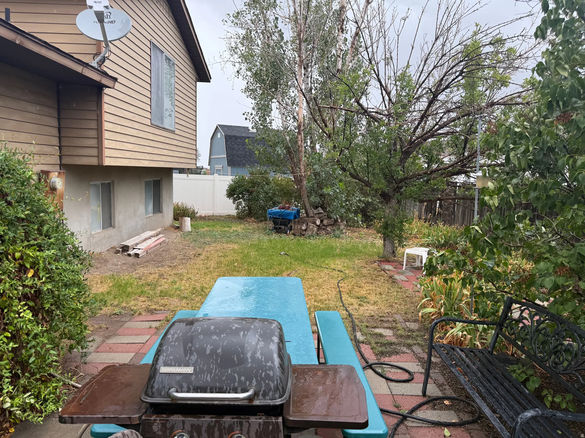 Rear yard with mature trees, shrubbery, and a paver patio