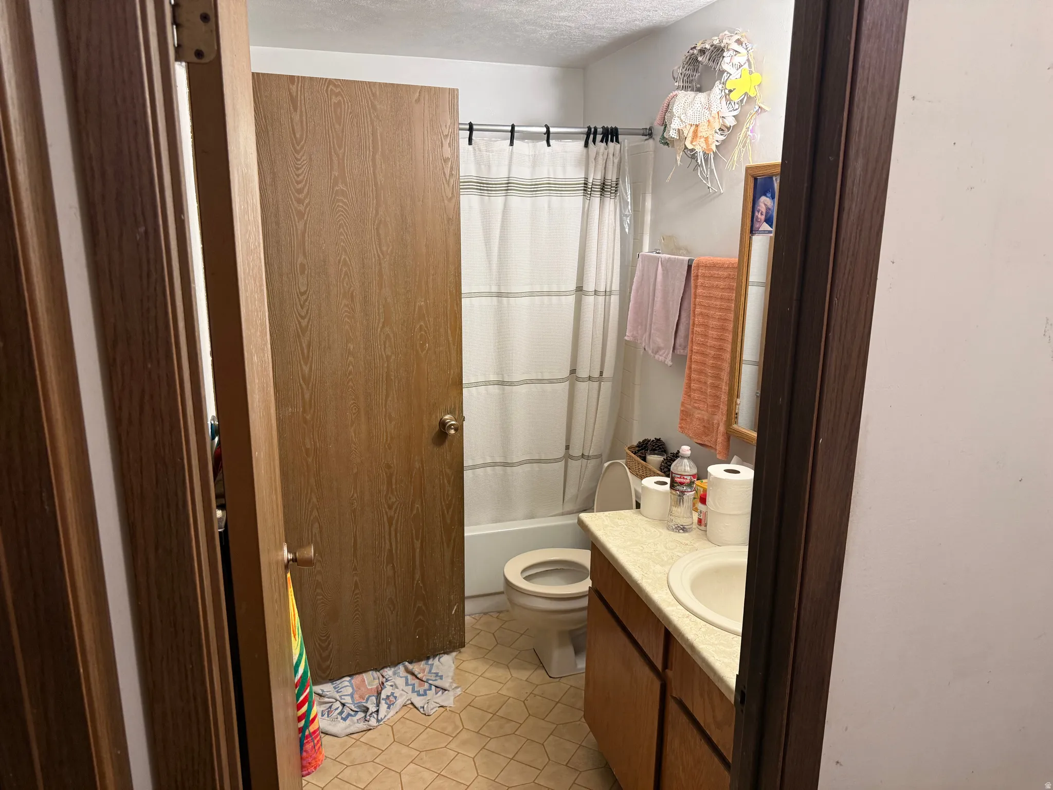 Bathroom featuring a single vanity with laminate countertop, integrated sink, wood-finish cabinetry, and a full-size tub with shower