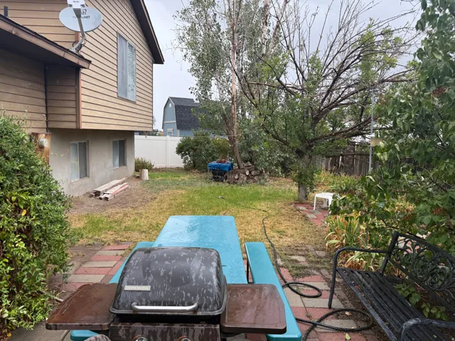 Rear yard with mature trees, shrubbery, and a paver patio