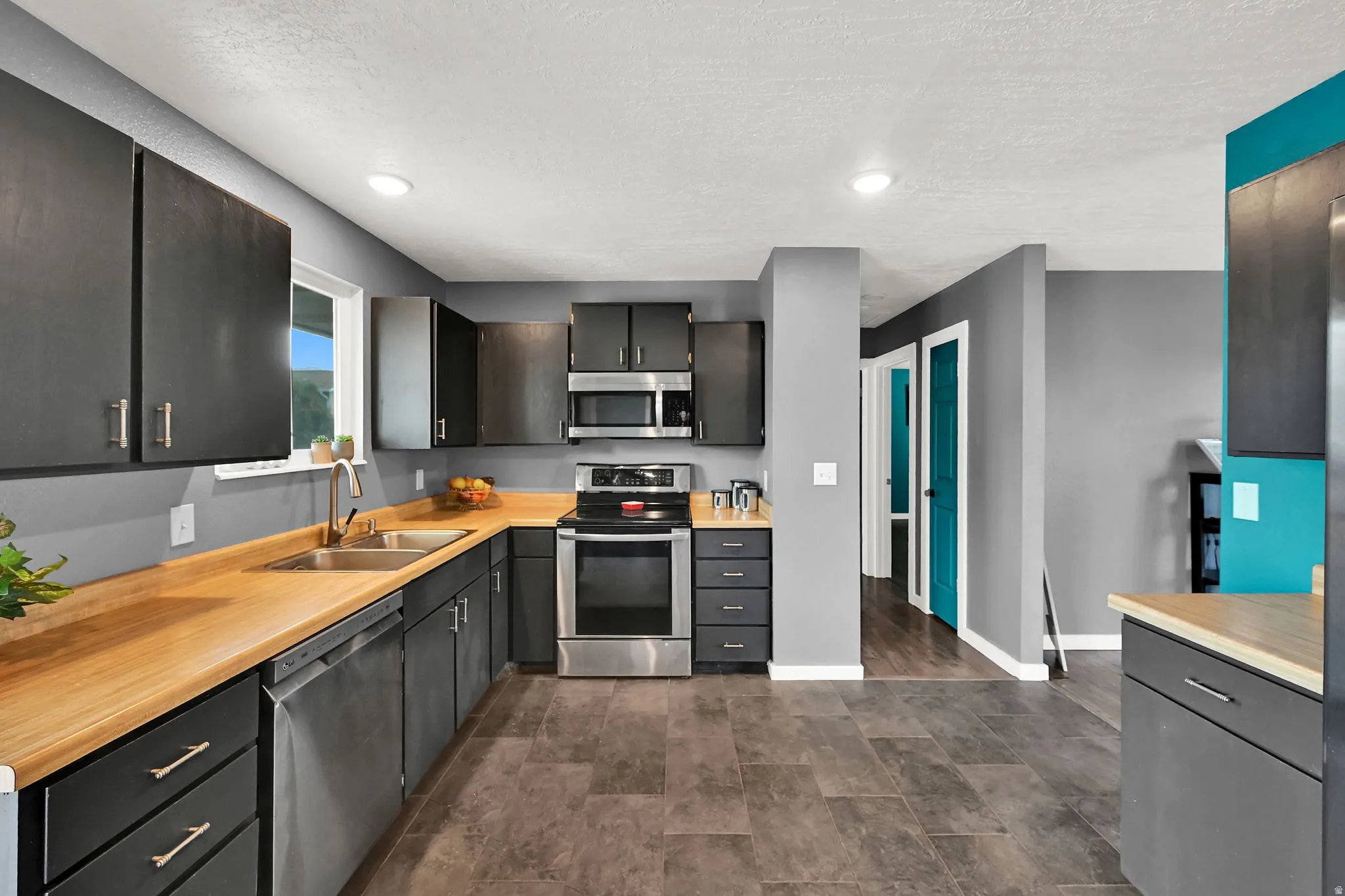 Kitchen featuring dark cabinetry, wood-finish countertops, stainless steel appliances, and recessed lighting