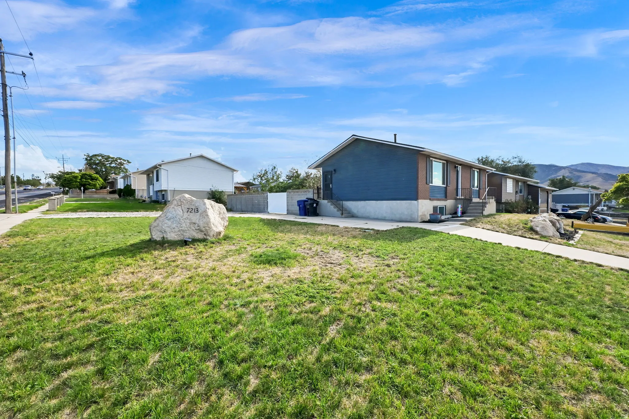 Single-story exterior with blue and brown siding, concrete driveway, and established front lawn