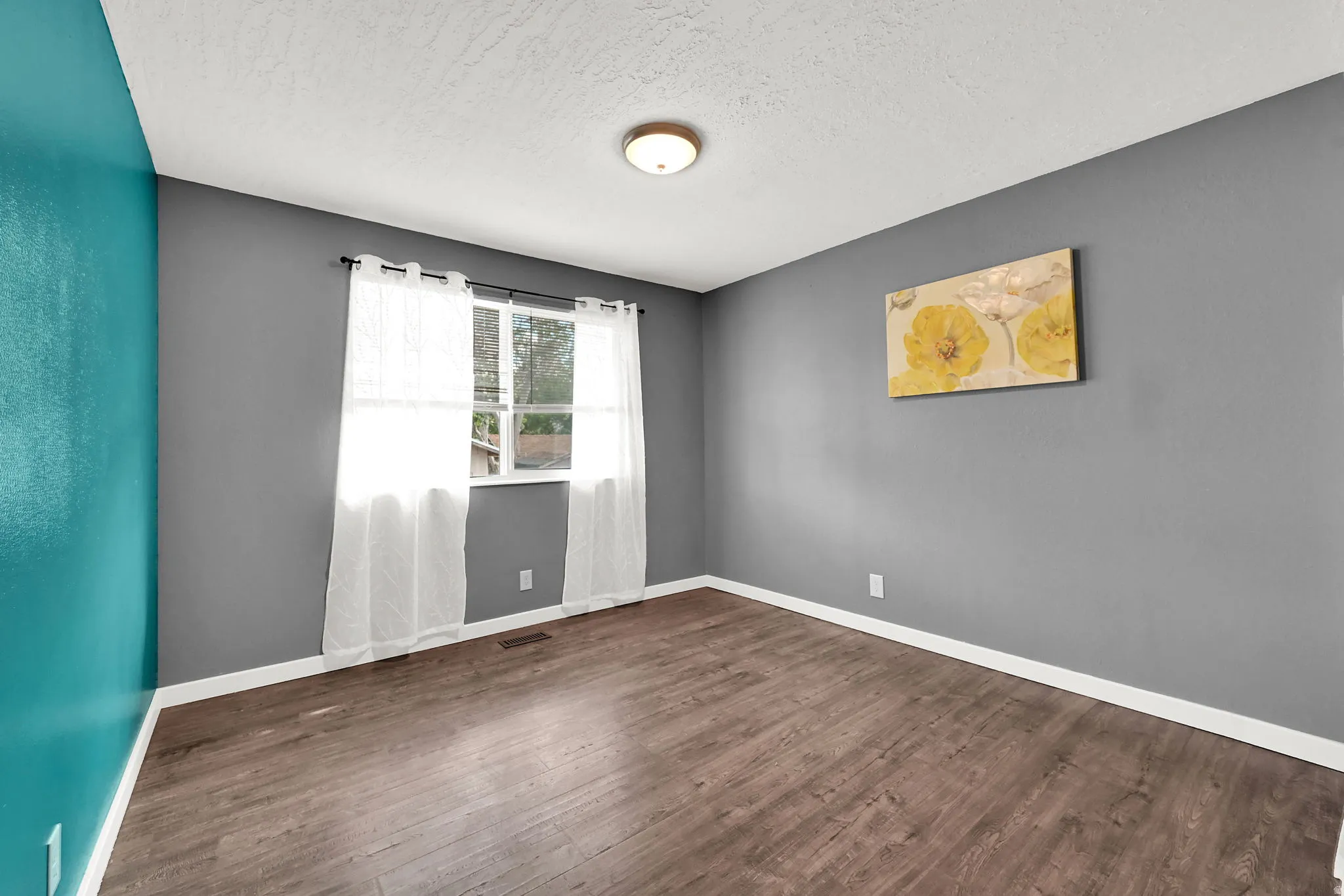 Wood-finish flooring, white trim, and a window with white casing