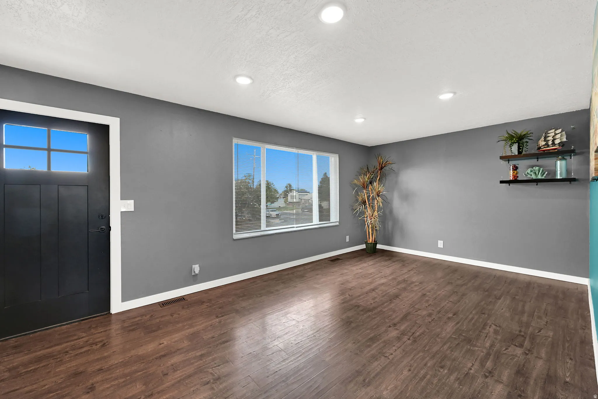 Wood-finish flooring, recessed ceiling lighting, a multi-pane front door, and a large window