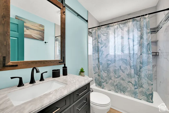 Bathroom featuring a vanity with a rectangular undermount sink, a wood-framed mirror, a built-in bathtub, and tiled walls with an accent strip