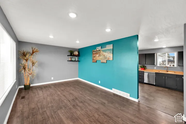 Recessed ceiling lighting, wood-finish flooring, two-tone painted walls, and built-in kitchen cabinetry with a stainless steel dishwasher