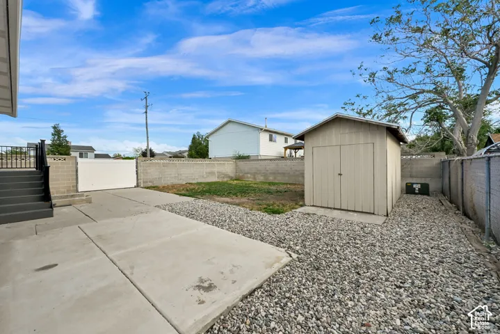 Expansive backyard with a concrete patio, gravel landscaping, and a detached storage shed