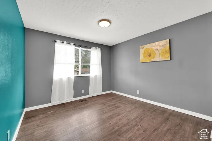 Wood-finish flooring, white trim, and a window with white casing
