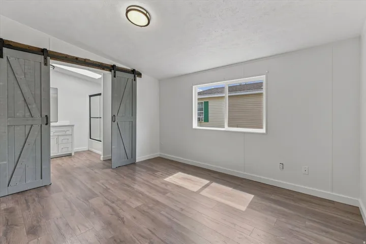 Wood-finish flooring throughout, bright white walls, and a window with white trim