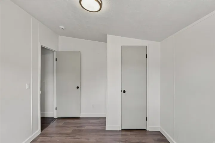 Bright hallway featuring multiple white panel doors with frosted glass inserts, wood-finish flooring, and clean white walls throughout