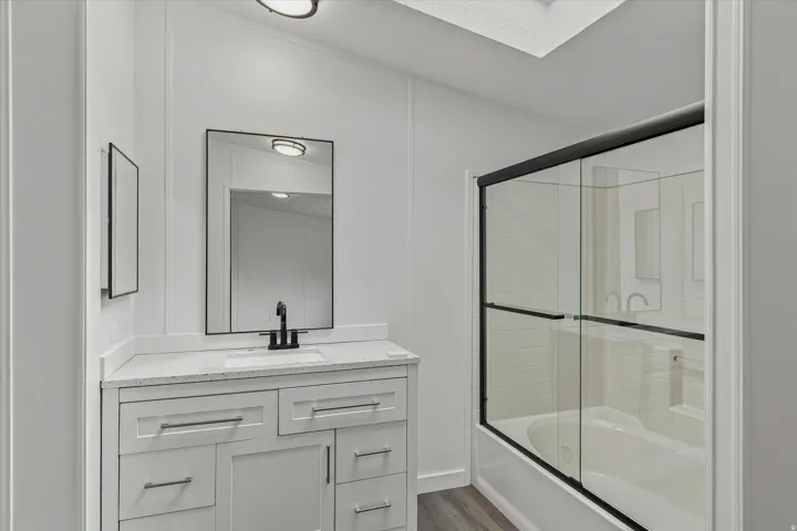 White shaker-style vanity with a light-toned countertop, rectangular undermount sink, and matte black faucet