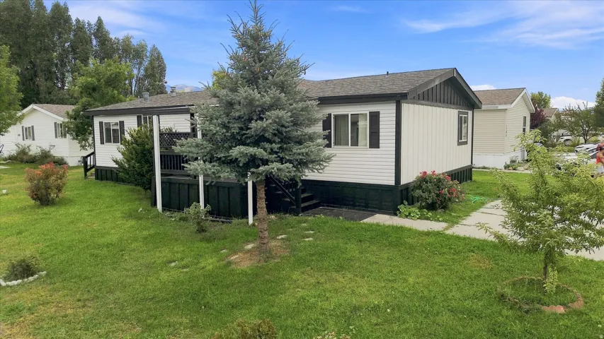 Modern manufactured home featuring a spacious single-story layout with board-and-batten exterior siding, elevated deck with under-deck storage, and gable roof design
