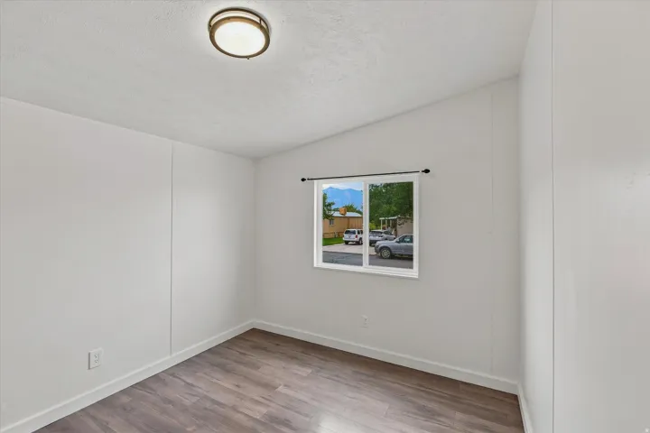 Wood-finish flooring with white baseboards, a white window frame, and a flush-mount ceiling light fixture