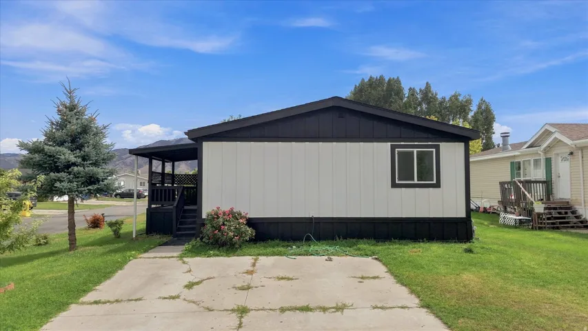 Modern manufactured home featuring a clean contemporary exterior with dark metal siding and trim, large window openings for natural light, and a covered entry porch