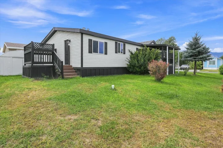 White horizontal siding exterior with black trim, an elevated rear deck, and a partially covered patio