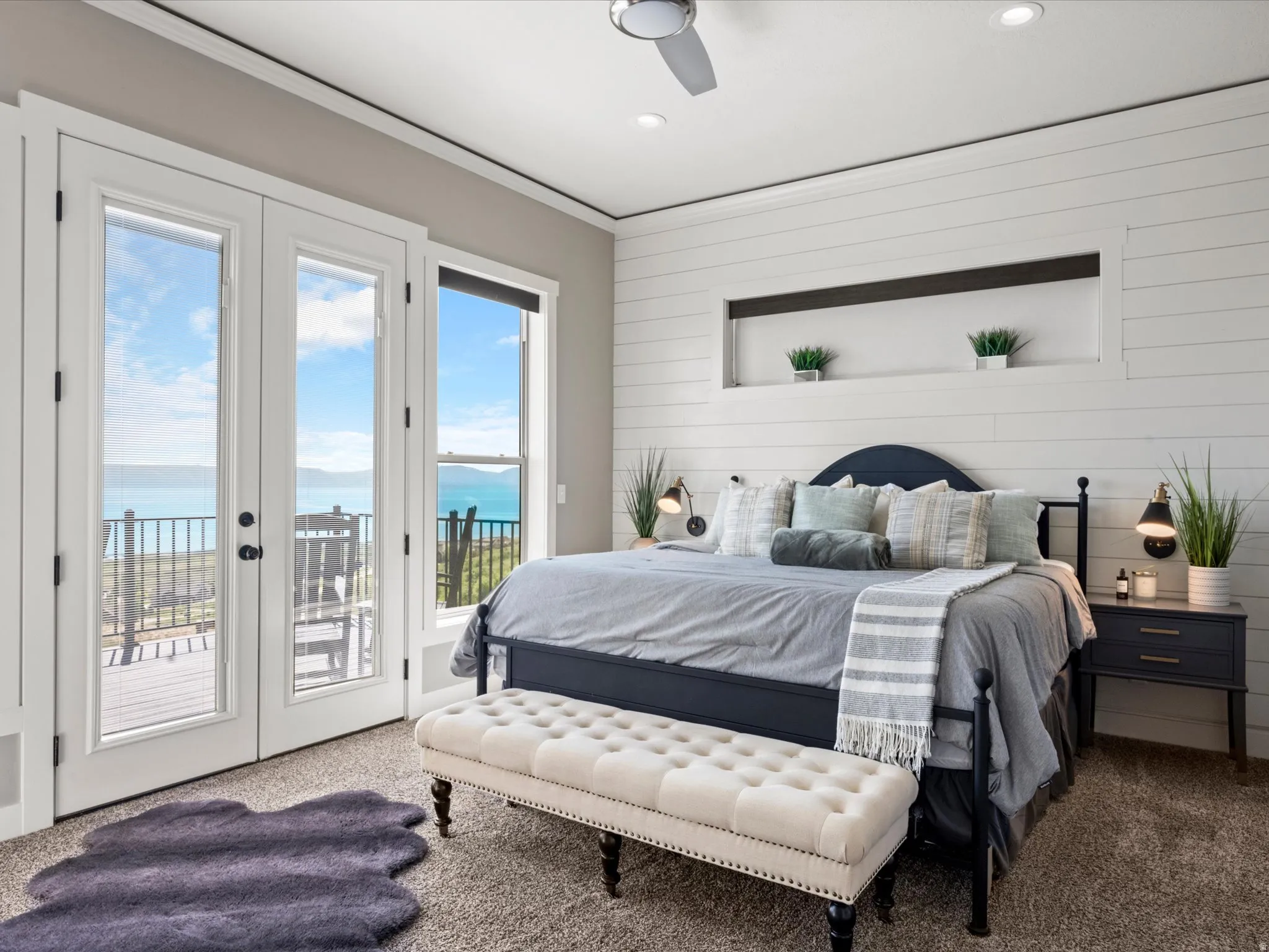French doors opening to an exterior deck, plank wall paneling with an integrated display niche, recessed lighting, and a ceiling fan