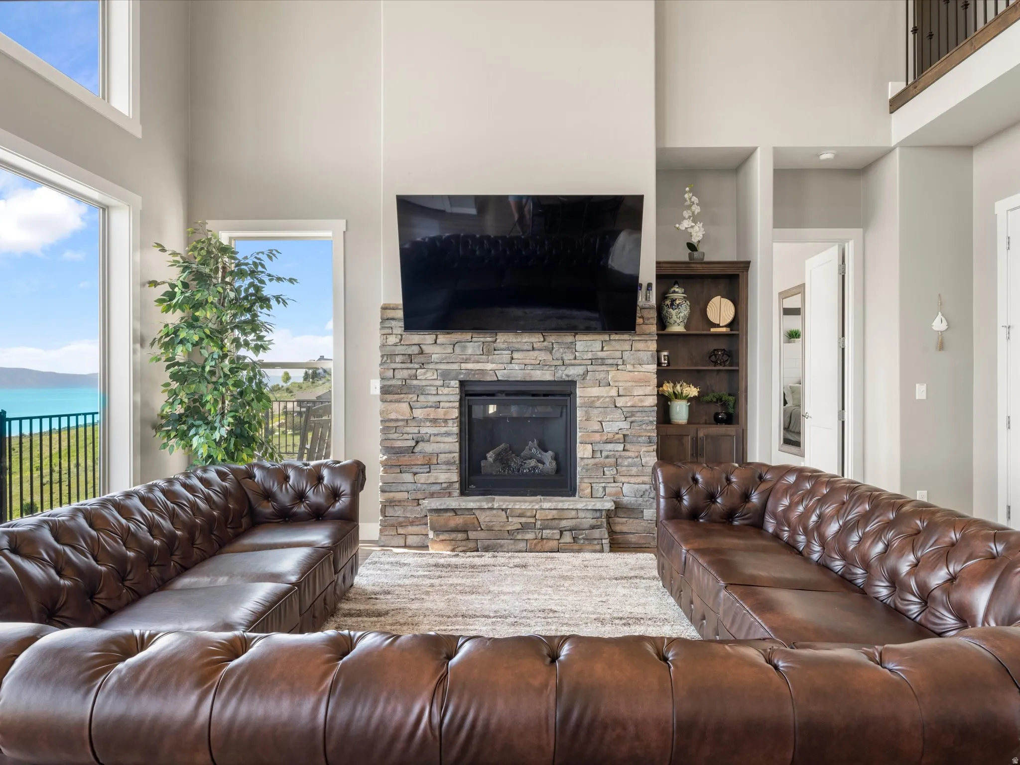Two-story living area with a stone-clad fireplace and built-in shelving