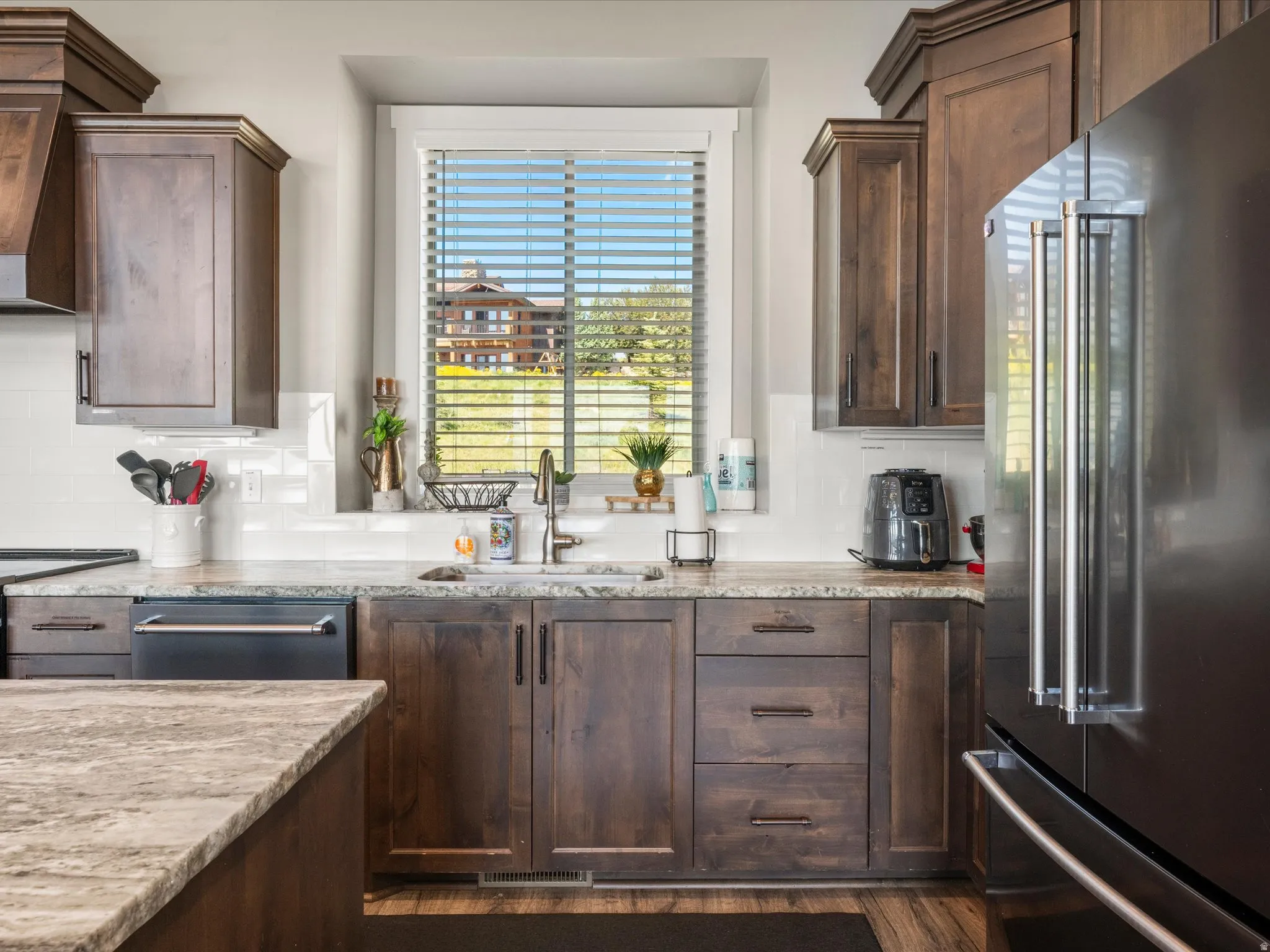 Chef's kitchen featuring rich wood cabinetry with multiple storage drawers, quartz countertops, stainless steel appliances including a built-in refrigerator, and a large center island with seating