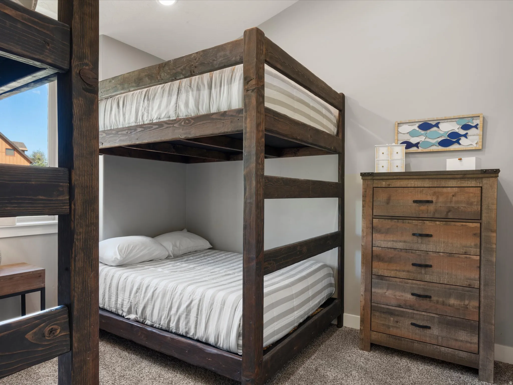 Built-in bunk beds with wood-finish framing, light gray walls, and plush carpet flooring