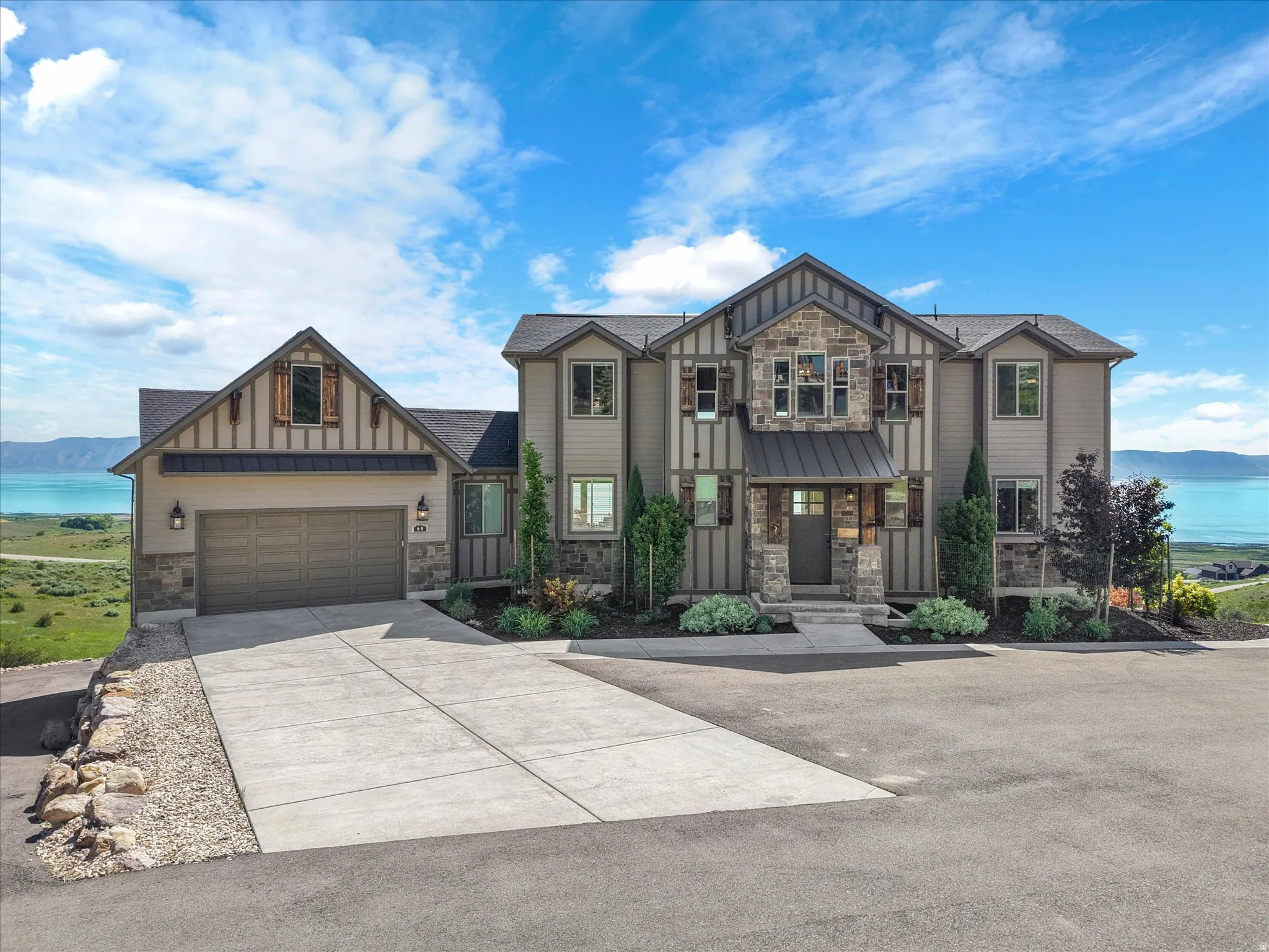 Stately multi-level residence with stone and siding facade, a prominent entryway, and an attached two-car garage