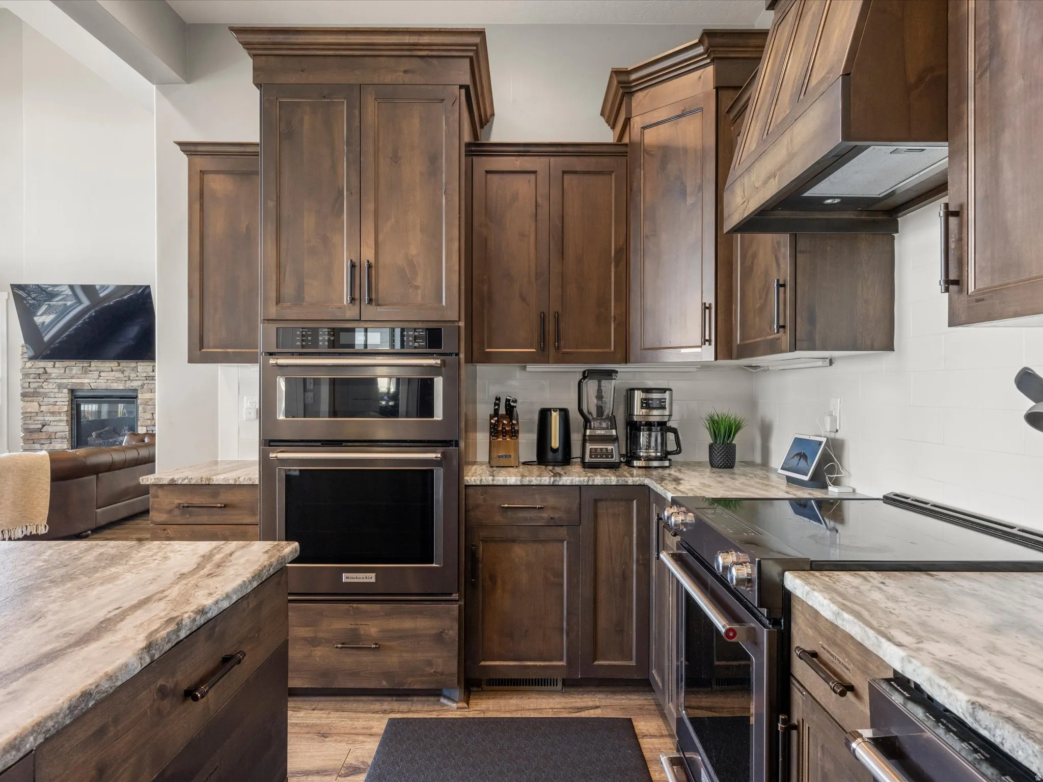 Gourmet kitchen featuring wood-finish cabinetry, stone countertops, stainless steel double ovens, and a matching stainless steel cooktop