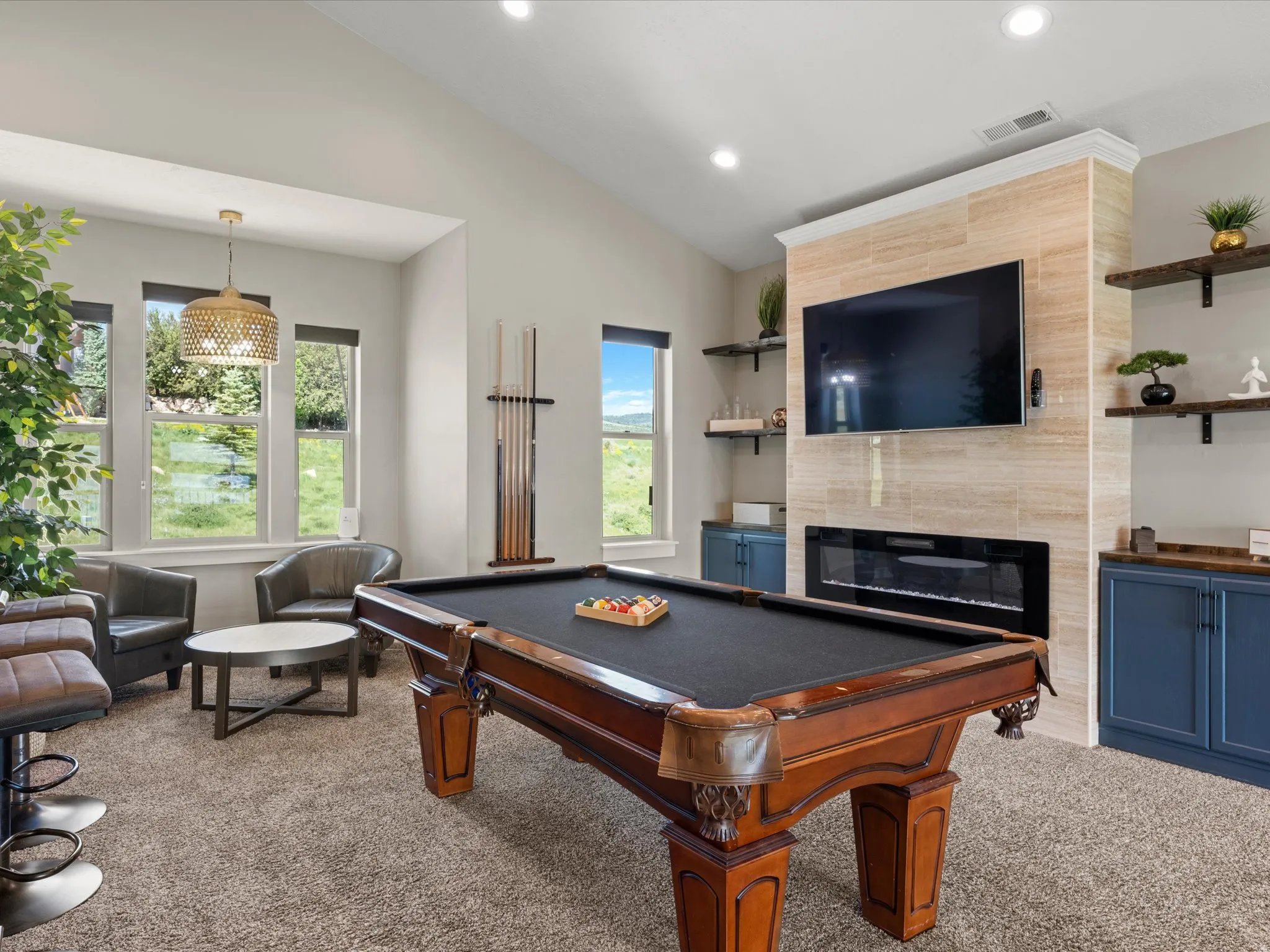 Vaulted ceiling with recessed lighting, linear electric fireplace, built-in cabinetry, and multiple windows