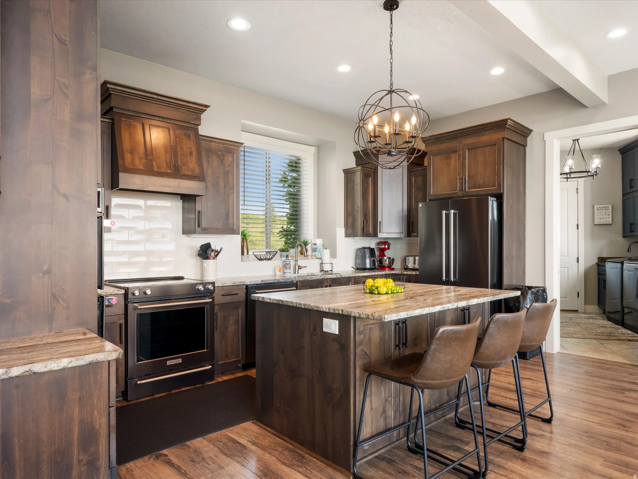 Kitchen featuring dark wood-finish cabinetry, a large center island with stone countertops, a spherical chandelier, recessed lighting, and wood-finish flooring