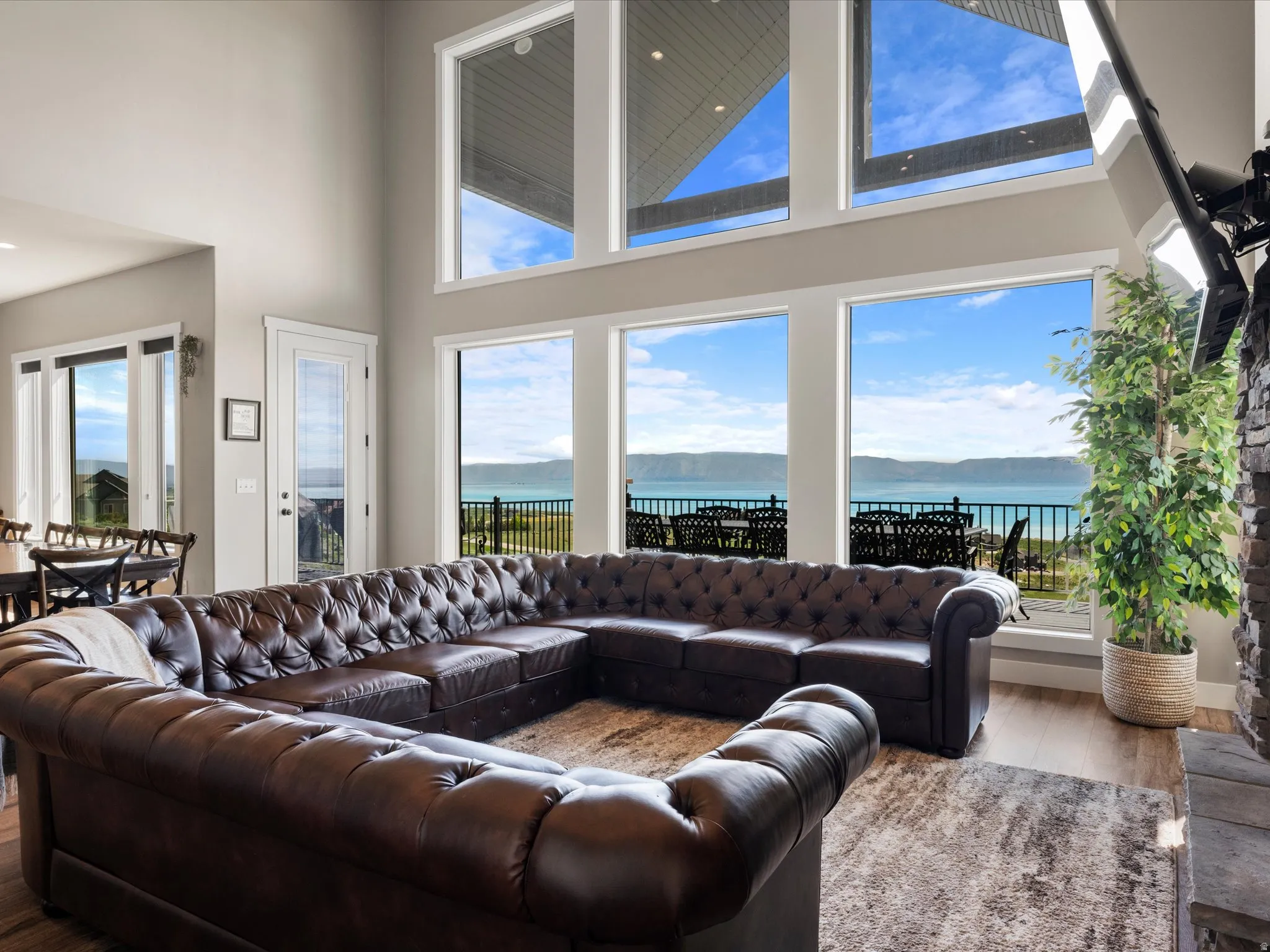 Two-story living area featuring extensive window walls, water frontage, and wood-finish flooring
