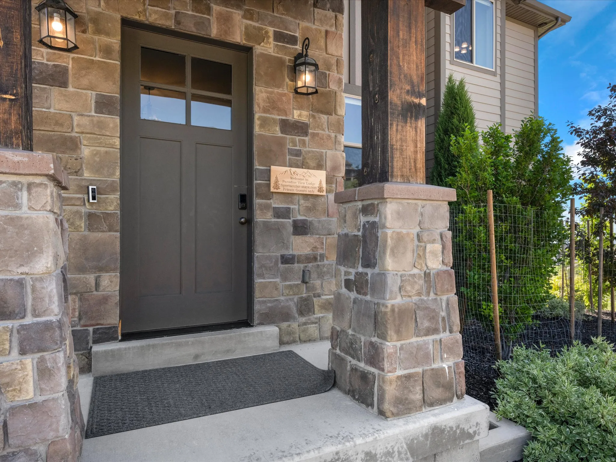 Stone veneer exterior with a dark-paneled entry door, transom windows, and exterior sconce lighting