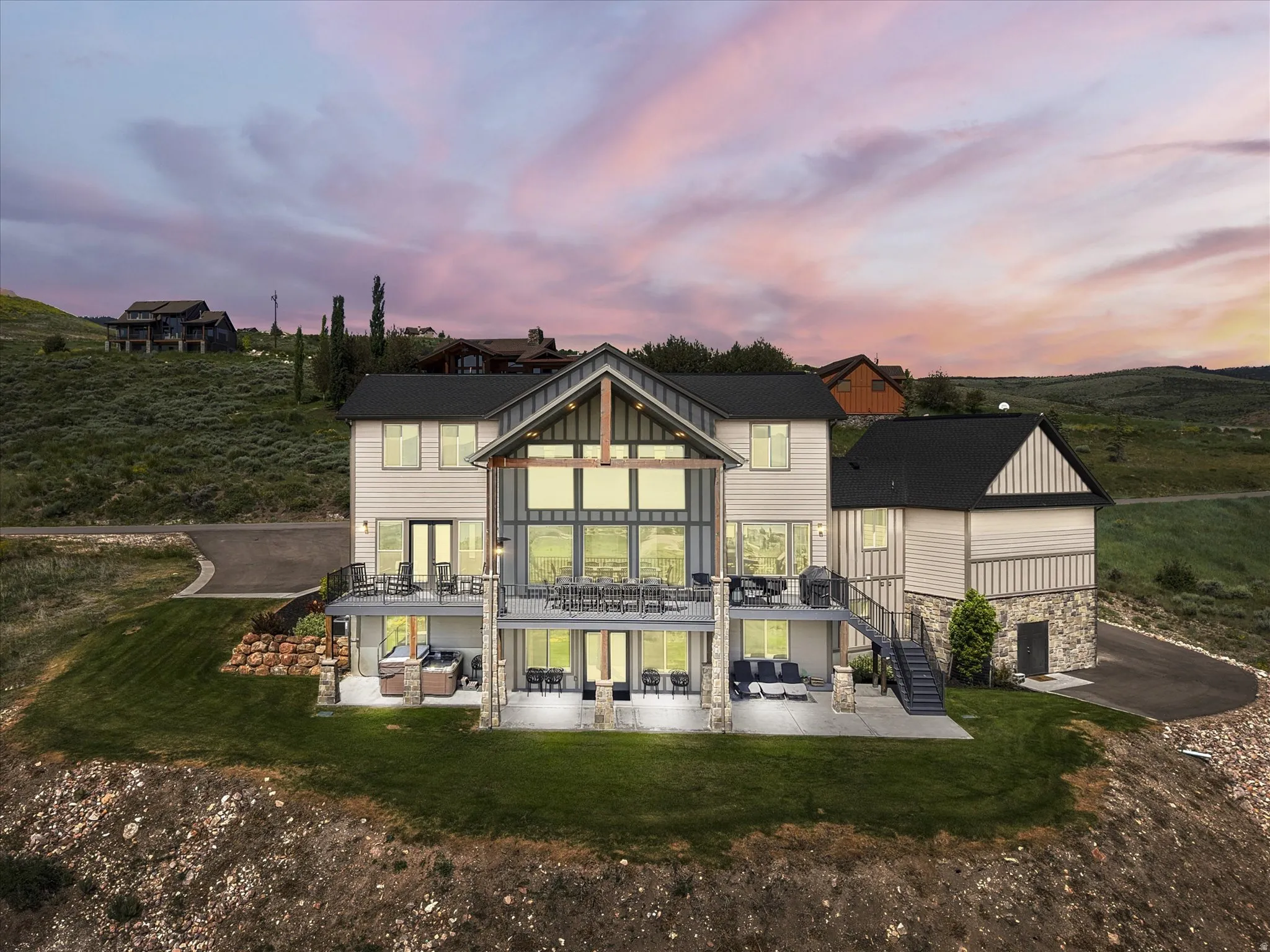 Multi-level exterior featuring extensive window arrays, two spacious outdoor decks, a stone-clad lower level, and a separate side entrance