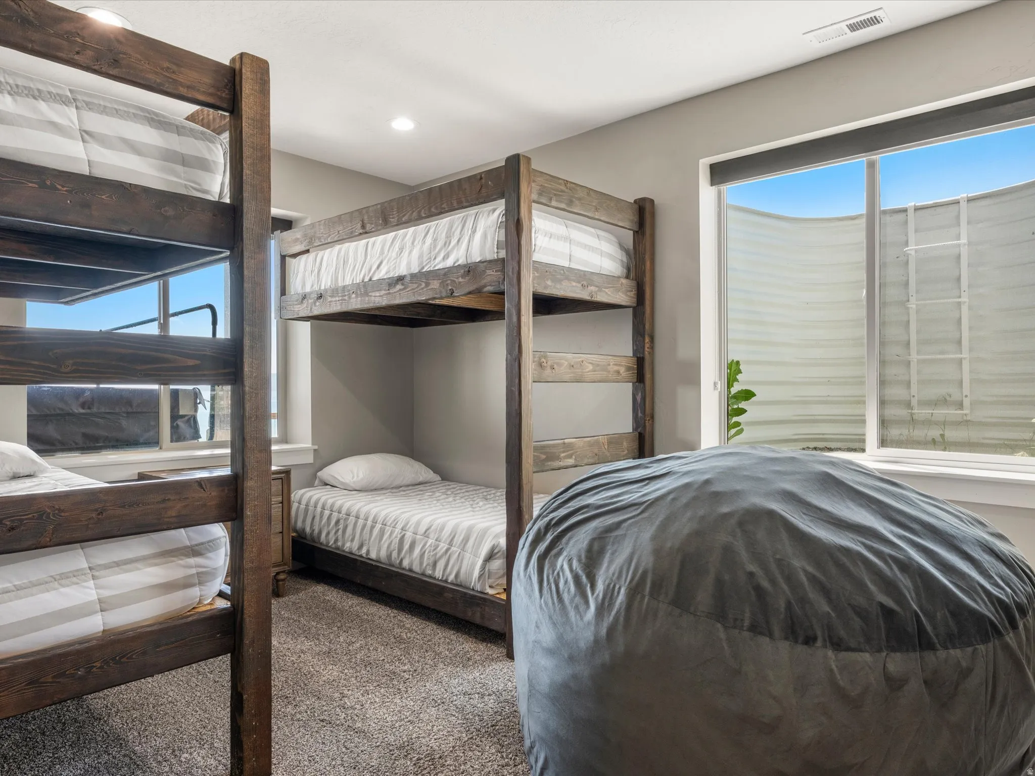 Recessed lighting, wood-finish bunk beds, and a large window with a window well