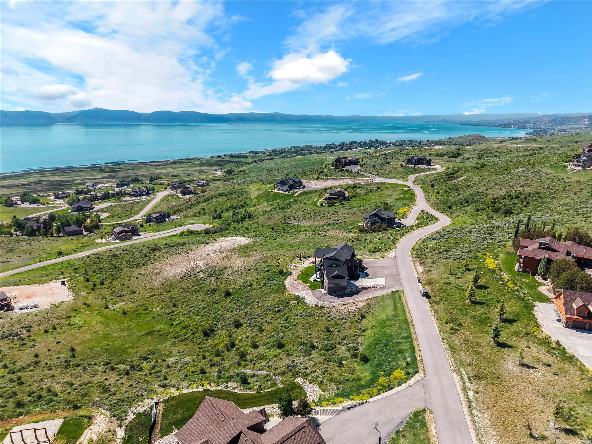Expansive residential landscape with paved roads, verdant hillsides, and distant lake