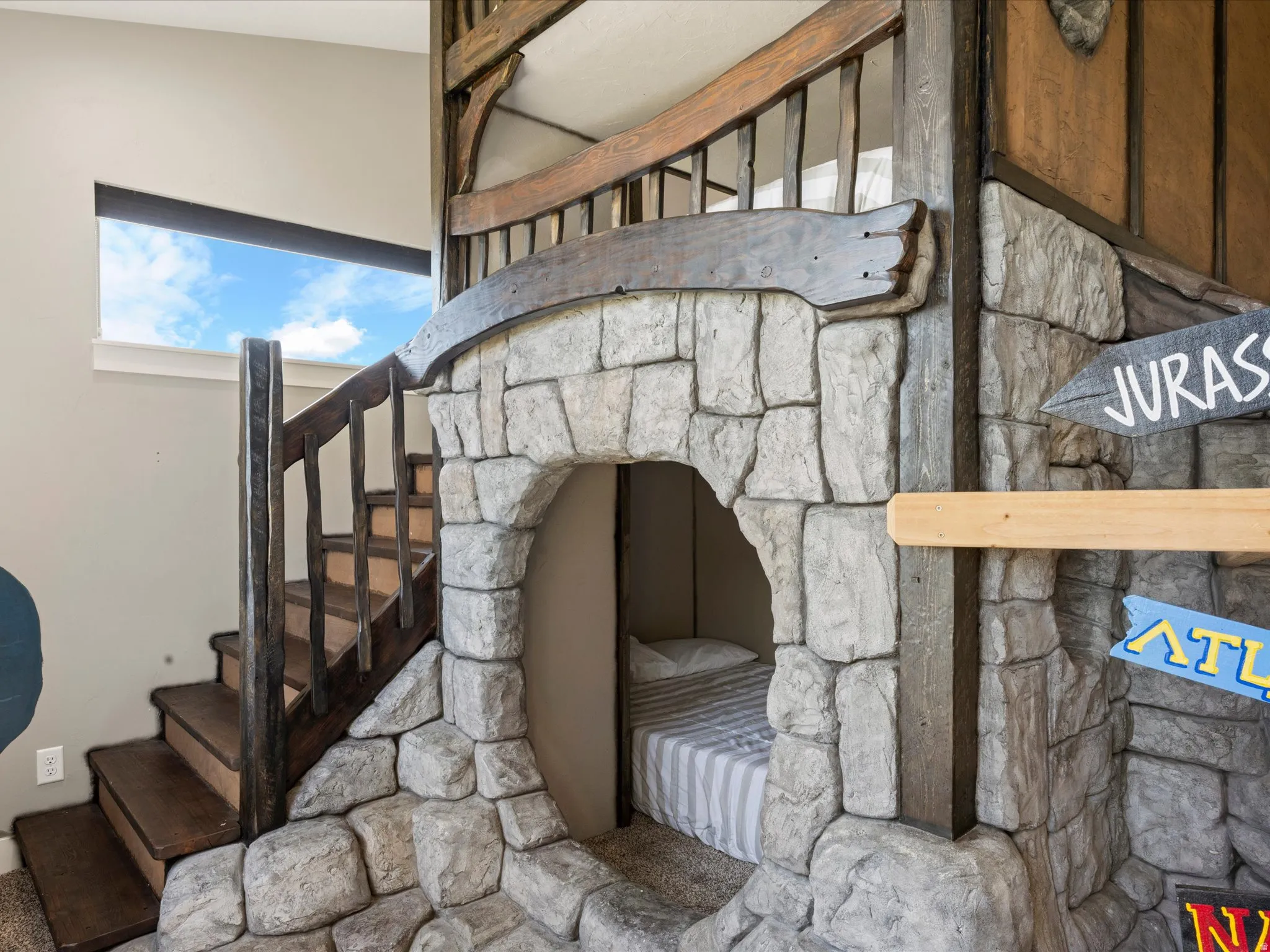 Built-in stone-look structure featuring a rounded entryway, integrated bed, and wooden steps with railings