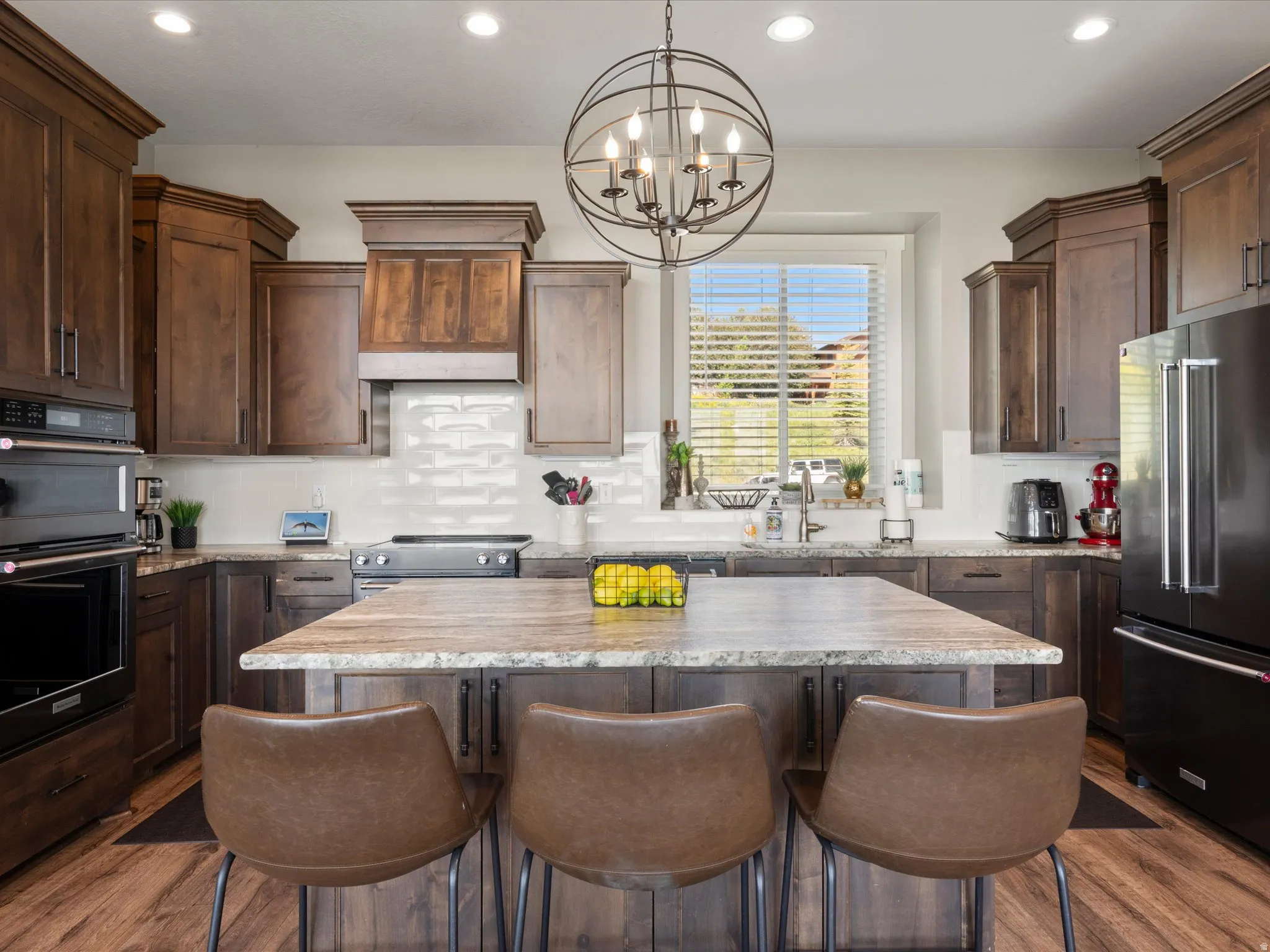 Kitchen featuring wood-finish cabinetry, a large center island with seating, a built-in oven and microwave, a tile backsplash, and recessed lighting