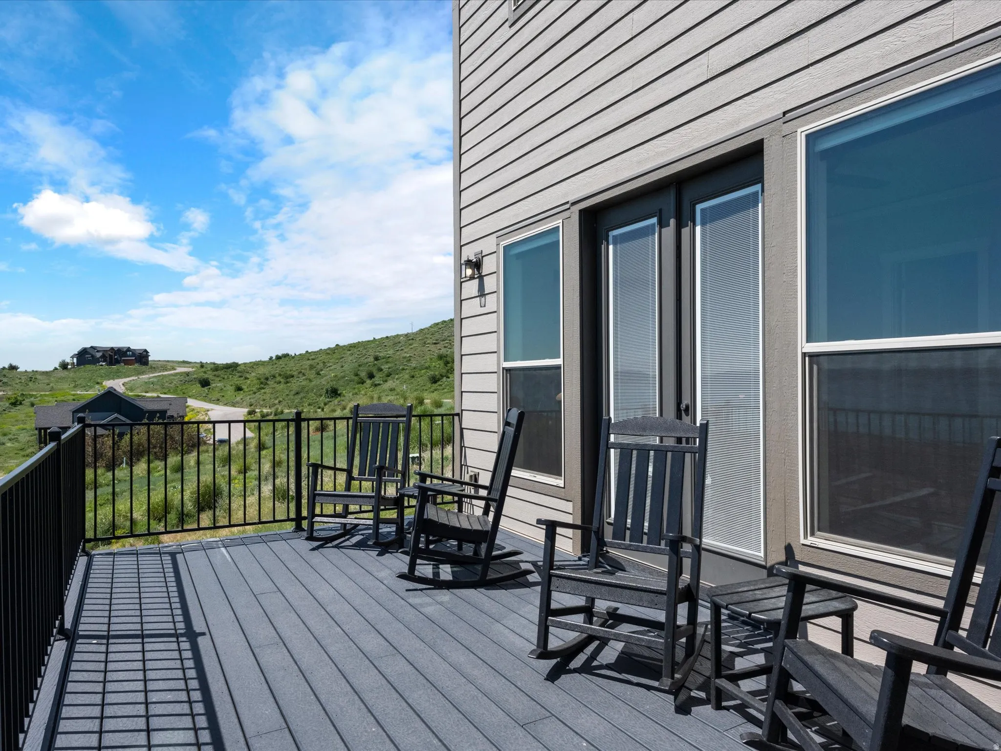Expansive outdoor deck with composite decking and black metal railing, featuring direct access via double glass doors