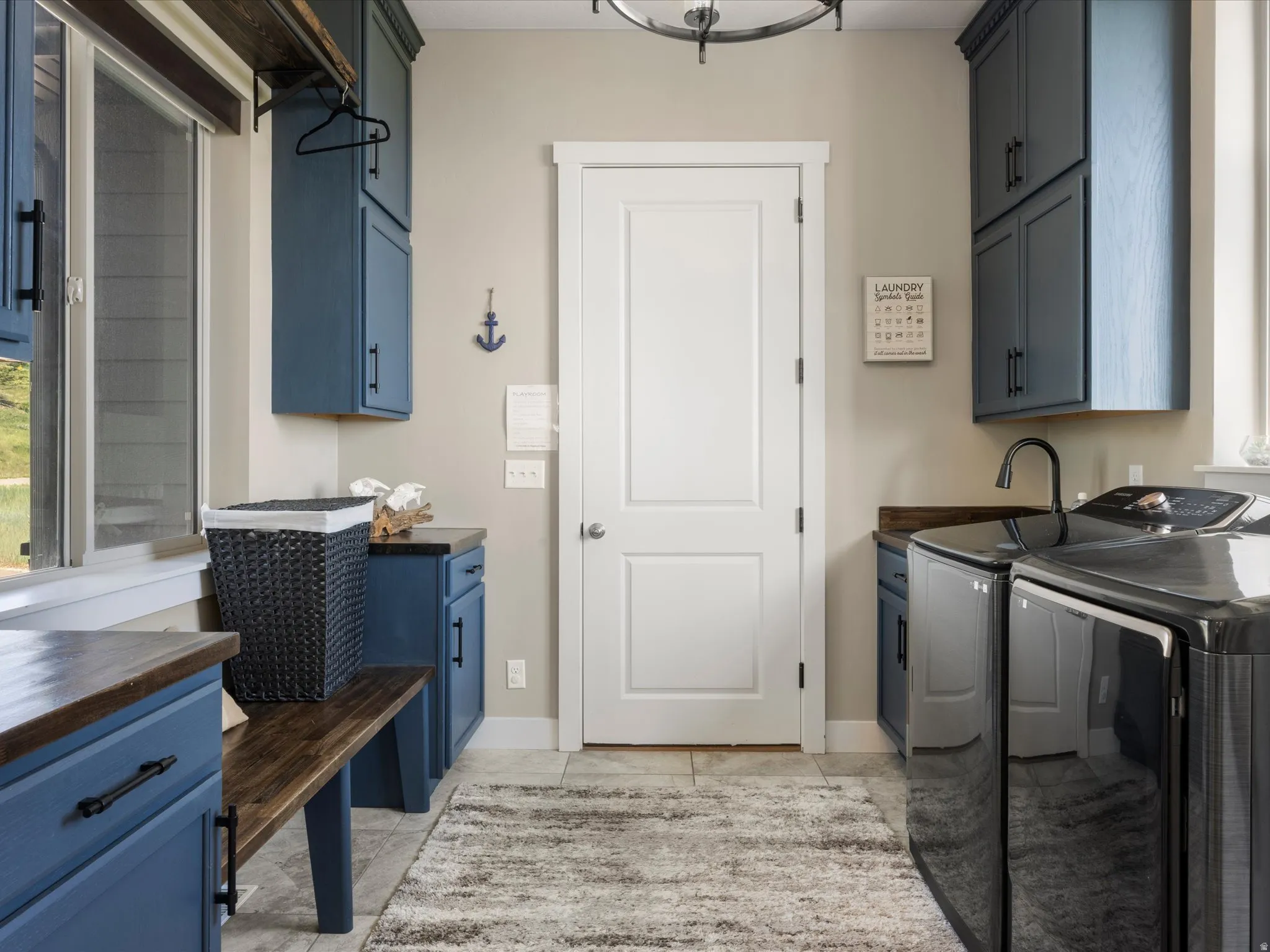 Laundry area featuring blue cabinetry, a built-in wooden bench, and a dark wood-finish countertop