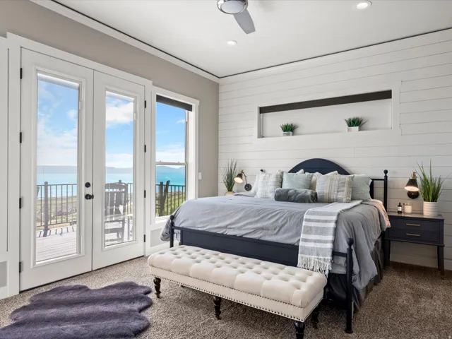 French doors opening to an exterior deck, plank wall paneling with an integrated display niche, recessed lighting, and a ceiling fan