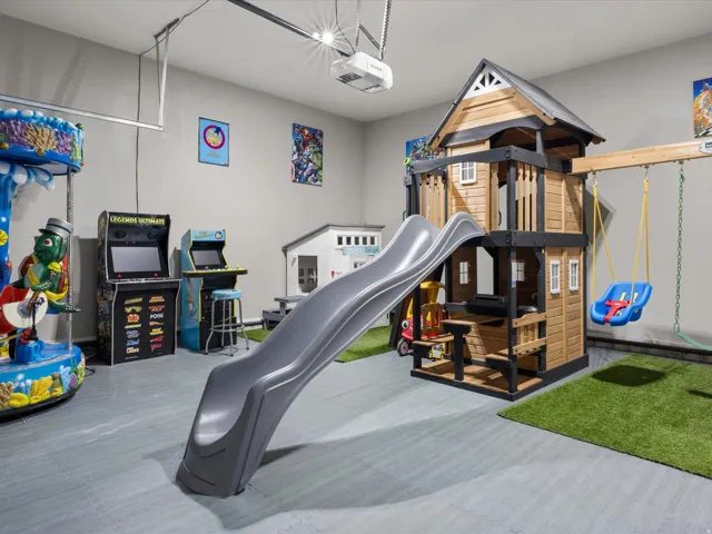 Interior space featuring a play structure with slide, swing set, and a designated artificial turf area