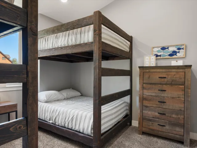 Built-in bunk beds with wood-finish framing, light gray walls, and plush carpet flooring