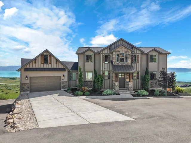 Stately multi-level residence with stone and siding facade, a prominent entryway, and an attached two-car garage