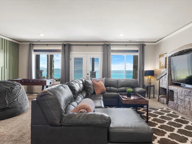 Stone-clad media console, recessed lighting, expansive windows, glass-paneled French doors, and textured accent wall