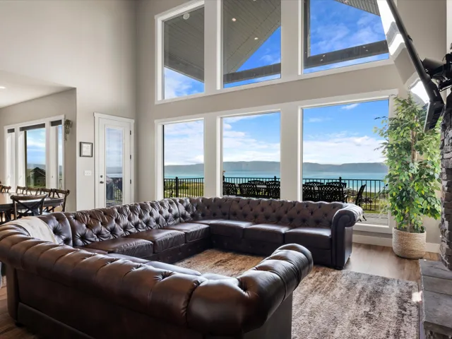 Two-story living area featuring extensive window walls, water frontage, and wood-finish flooring