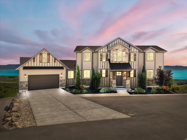 Craftsman-style exterior featuring stone accents, a multi-pane front door, a metal awning, and a two-car garage
